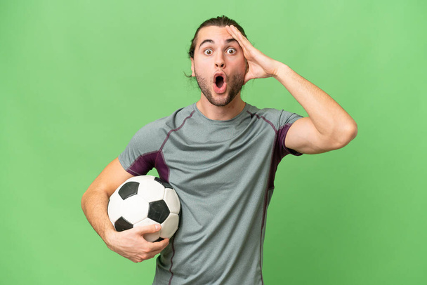 Joven jugador de fútbol guapo hombre sobre fondo aislado con expresión sorpresa - Foto, imagen