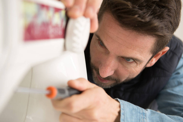 man using screwdriver change type of sewing-machine foot - Фото, изображение
