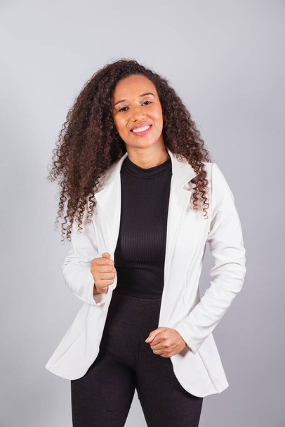 vertical photo, beautiful black Brazilian woman, businesswoman, wearing white suit, smiling, optimistic. - Φωτογραφία, εικόνα