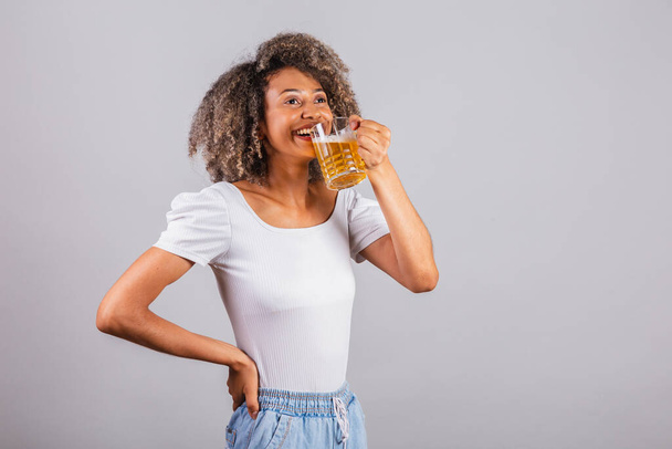 beautiful black brazilian woman in casual clothes holding glass of beer. - Photo, Image