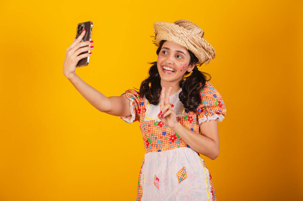 Beautiful brazilian woman, with festa junina clothes, taking self portrait with smartphone. - Foto, Imagem