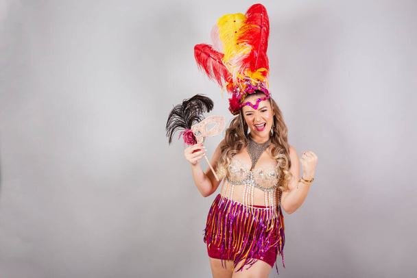 Horizontal, half body shot, beautiful Brazilian woman in carnival clothes. holding carnival mask. - Foto, Bild