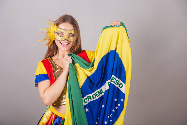 Brazilian blonde woman, dressed in frevo clothes, carnival mask, holding flag of Brazil. - Valokuva, kuva