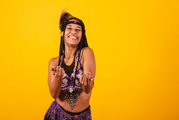 beautiful black Brazilian woman, in purple carnival clothes, inviting with hands. - Foto, imagen