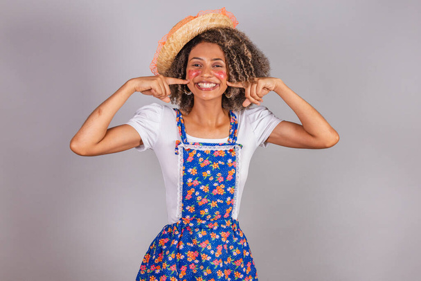 Young black Brazilian woman, with country clothes, dressed for Festa Junina. Saint John's festival. pointing to mouth, kissing booth. - Zdjęcie, obraz