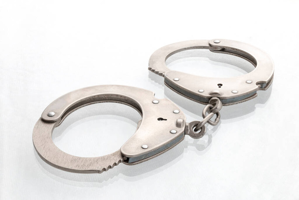 Пара стальных наручников закрываются, серебряные металлические наручники на белом - Фото, изображение