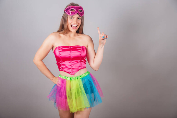 Brazilian blonde woman dressed in pink carnival clothes. having an idea finger raised. - Zdjęcie, obraz