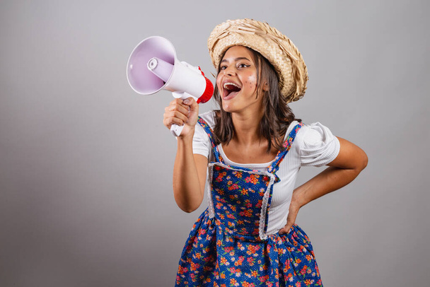 Brazilian woman wearing country clothes, So Joo party, Junina party. with megaphone announcing promotions and advertisements.  - Foto, afbeelding