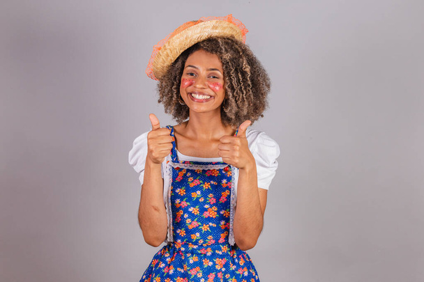Young black Brazilian woman, with country clothes, dressed for Festa Junina. Saint John's festival. thumb finger raised, optimistic, happy, positive. - Photo, image