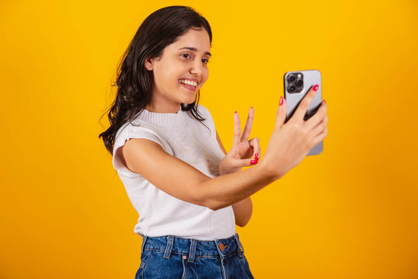 beautiful brazilian woman holding smartphone, taking self portrait, selfie. - Фото, изображение