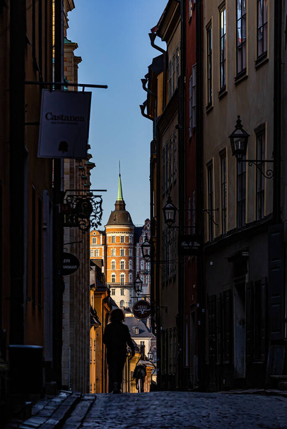 Stockholm, Sweden A woman in silhouette walks her dog on a narrow street, Kindstugatan,  in Gamla Stan or Old Town. - Foto, imagen