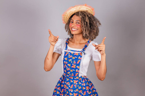 Young black Brazilian woman, with country clothes, dressed for Festa Junina. Saint John's festival. optimistic and confident pointing to the skies. - Foto, immagini