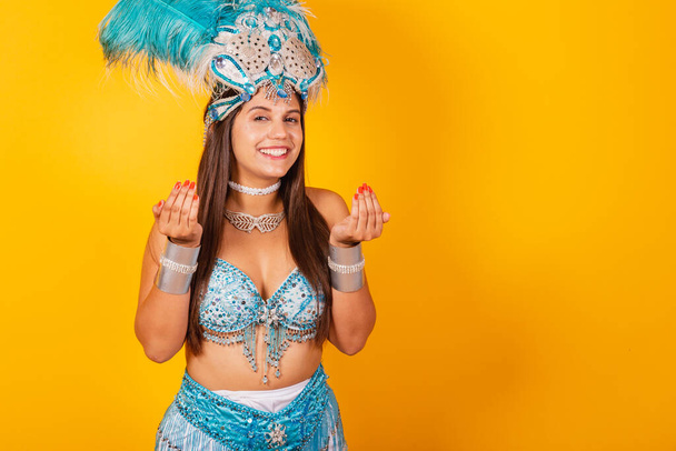 Beautiful Brazilian woman in blue and white carnival clothes. with crown of feathers, inviting with hands. - Photo, Image