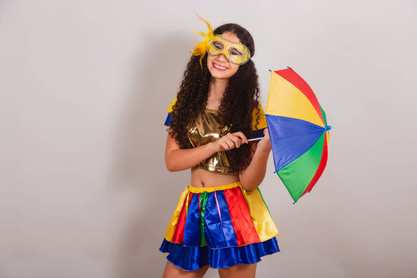young teen girl, brazilian, with frevo clothes, carnival. holding frevo umbrella. posing for photo. - Foto, Imagem