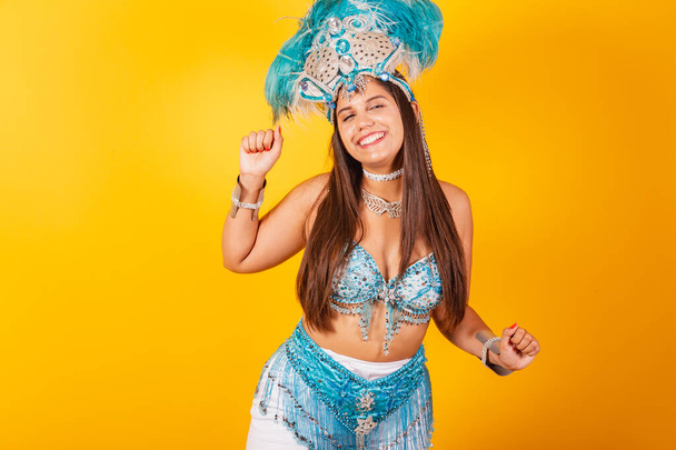 Beautiful Brazilian woman in blue and white carnival clothes. with crown of feathers, dancing. - Zdjęcie, obraz