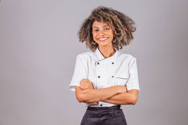 若い黒ブラジルの女性、料理人、マスターシェフ、レストランの制服を着て。腕が交差し楽観的で自信があり. - 写真・画像