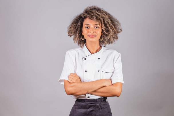 Young black Brazilian woman, cook, masterchef, wearing restaurant uniform. arms crossed, optimistic and confident. - Fotó, kép