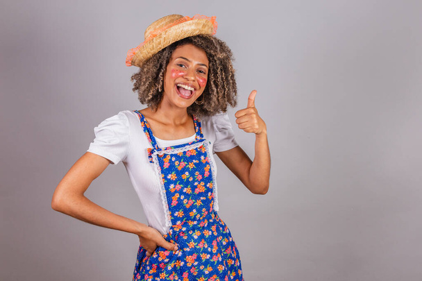 Young black Brazilian woman, with country clothes, dressed for Festa Junina. Saint John's festival. thumb finger raised, optimistic, happy, positive. - Fotografie, Obrázek