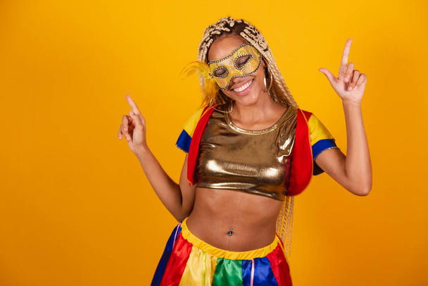 beautiful black Brazilian woman, dressed in carnival clothes, mask. yellow background. dancing, celebrating. - Fotografie, Obrázek