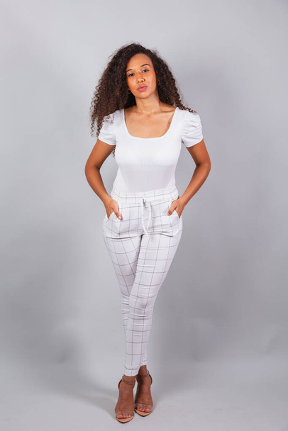 vertical photo, beautiful black Brazilian woman, dressed in white, casual clothes, facing the camera, serious, fashion. - Valokuva, kuva