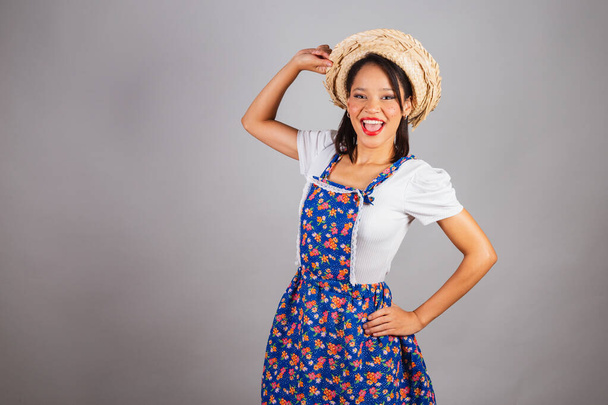 Brazilian woman, northeastern, with June party clothes, straw hat. Hands on waist and hat. - 写真・画像