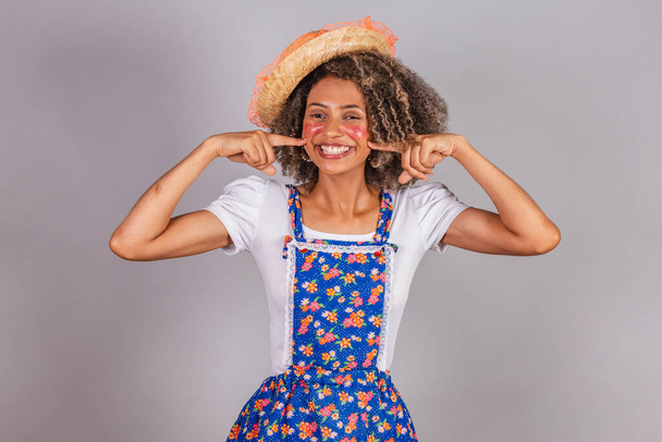 Young black Brazilian woman, with country clothes, dressed for Festa Junina. Saint John's festival. pointing to mouth, kissing booth. - Фото, зображення
