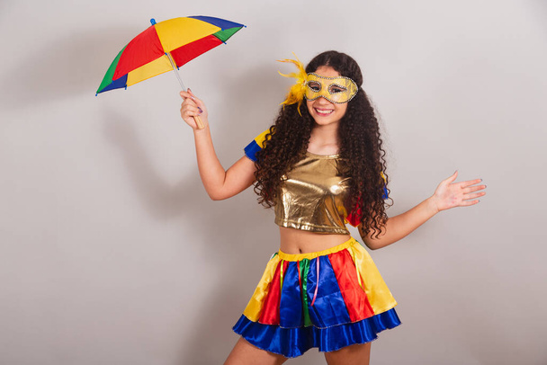 young teen girl, brazilian, with frevo clothes, carnival. holding frevo umbrella. dancing. - Foto, Bild