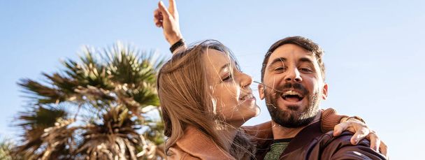 Horizontal banner or header with hipster young couple having fun taking a selfie portrait against a beautiful panorama at sunset. Boyfriend and girlfriend in love smiling at the camera together. - Foto, Imagem