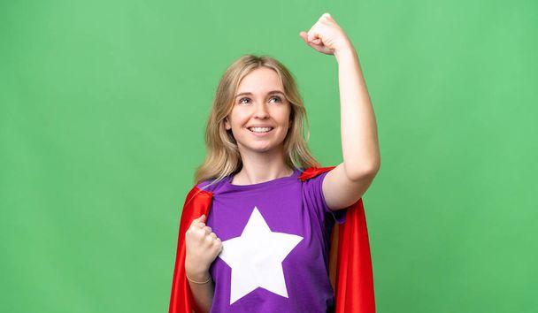 Giovane donna inglese su sfondo isolato in costume da supereroe e celebrare una vittoria - Foto, immagini