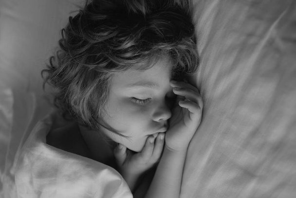 Cute kids sleep on white bed. Kid in bedroom sleeping on bed with white sheet and pillow - Φωτογραφία, εικόνα