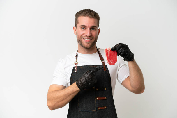 Butcher caucasian man wearing an apron and serving fresh cut meat isolated on white background pointing to the side to present a product - Photo, image