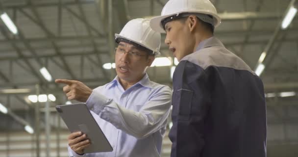 bukósisakot viselő férfi munkavállalók a gyárban - Felvétel, videó