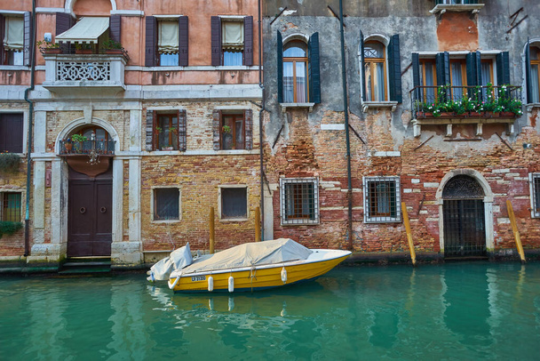 ヴェネツィアの運河の家の隣に水の中に駐車雨からカバーボート。水輸送と輸送のテーマ。ヴェネツィアでの朝. - 写真・画像
