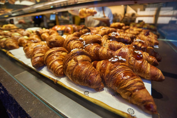 Close up view - assortment of freshly baked croissants for sale on counter of shop, market, cafe or bakery. Dessert, pastry, breakfast, sweet food and traditional french cuisine concept - Foto, afbeelding