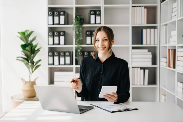 Confident businesswoman with laptop on desk in creative office - Zdjęcie, obraz