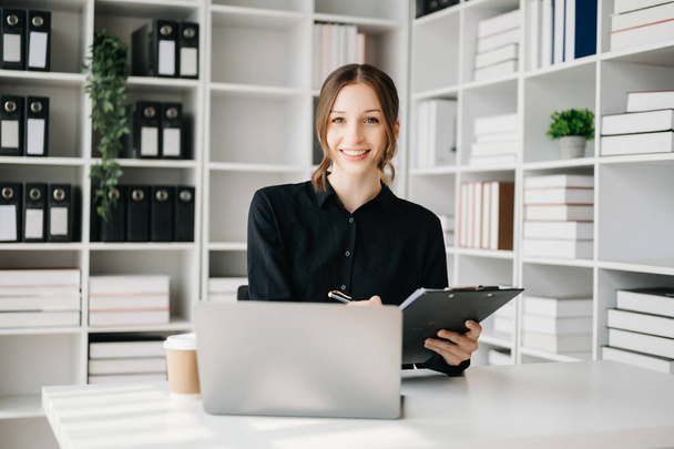 Confident businesswoman with laptop and clipboard  in creative office - Foto, Imagem