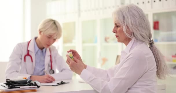 Therapeutin gibt älteren Patientinnen in Klinik Glas mit Medikamenten Cardio-Pillen für Kranke - Filmmaterial, Video
