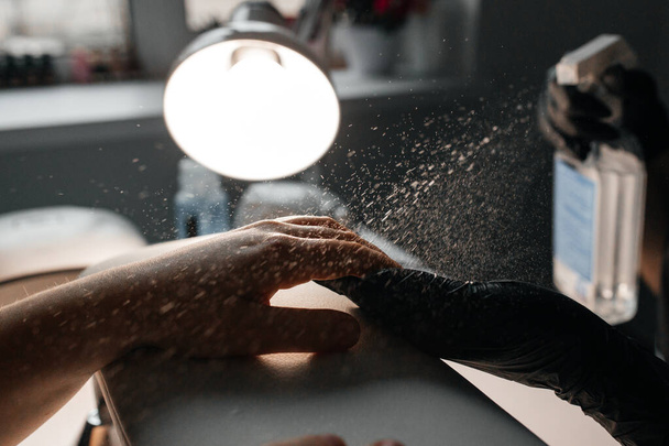 Manicurist disinfects client's hands in salon - Foto, Imagen