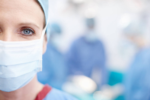 Making miracles happen everyday. Cropped closeup of a mature female surgeon wearing hospital scrubs and a protective face mask - Copyspace - Foto, imagen