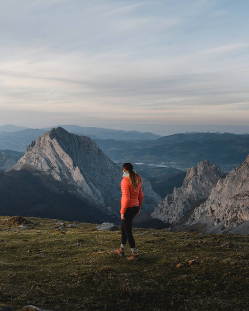Girl walks at sunset through the mountains of Duranguesado with rock peaks in the background. - Φωτογραφία, εικόνα