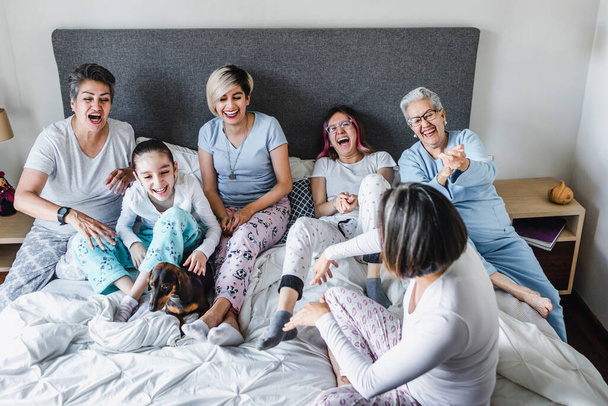 femmes latines famille grand-mère, mère, fille et enfants s'amuser sur le lit à la maison en Amérique latine, hispanique famille multigénérationnelle  - Photo, image
