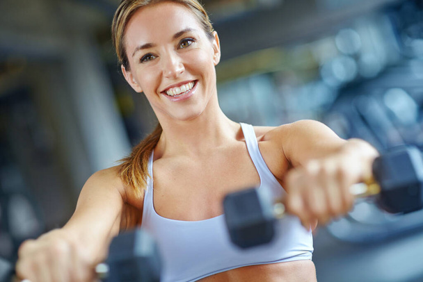Im making great progress. A beautiful young woman working out at the gym - 写真・画像