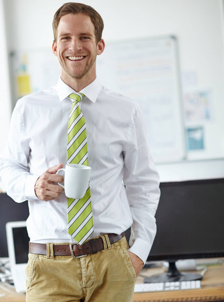 In the office bright and early. A handsome young businessman drinking coffee in his office - Foto, Imagem