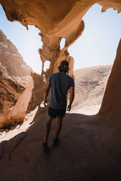 man walking into the spectacular rock formations of a desertic sandstone canyon in Fuerteventura - Zdjęcie, obraz