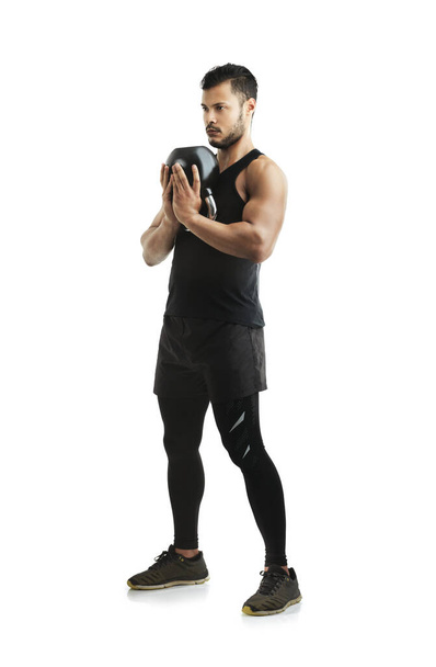 Hes committed to his fitness goals. Studio shot of a fit young man working out with a kettle bell against a white background - Foto, afbeelding