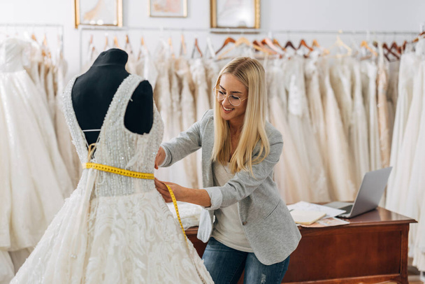 A beautiful tailor is working on a new wedding dress. - Foto, Imagem