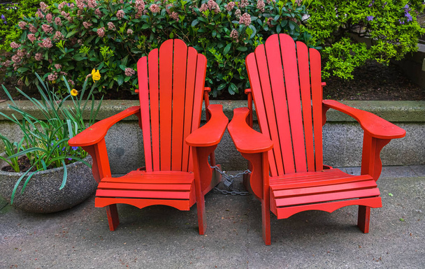 Rosso Adirondack sedia impostazione in giardino. Tradizionale sedia da spiaggia in legno rosso curveback, patio esterno adirondack sedie con schienali sagomati - Foto, immagini