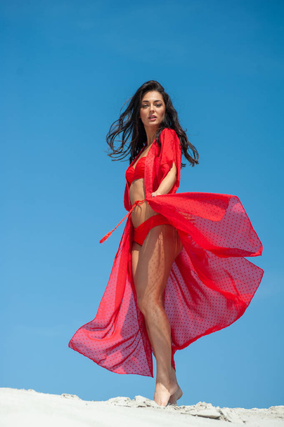 beautiful young woman in red dress posing on the beach - Valokuva, kuva