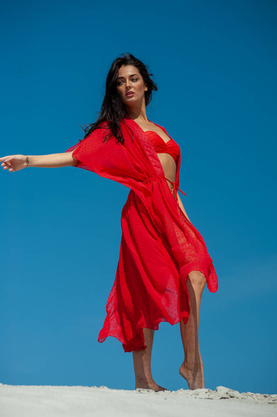 beautiful young woman in red dress posing on the beach - Фото, зображення