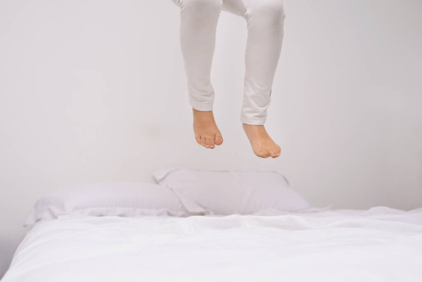 À quelle hauteur pouvez-vous aller ? les jambes d'une petite fille sautant sur le lit - Photo, image